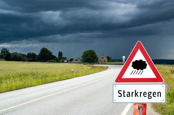 Bild vergr&ouml;&szlig;ern: Warnschild Starkregen an der Straße vor grauem Wolkenhimmel