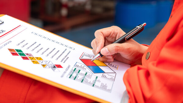 Bild vergr&ouml;&szlig;ern: A safety engineer is using pen to rating the health risk assessment level of chemical hazardous material in the paperwork form. Industrial safety working scene, close-up and selecitve focus