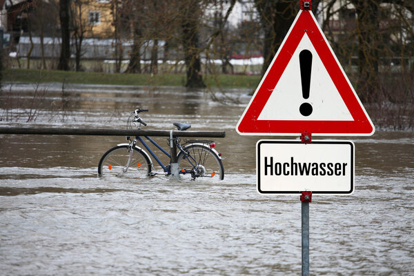 Bild vergr&ouml;&szlig;ern: Warnschild mit der Aufschrift "Hochwasser" steht an überfluteter Straße