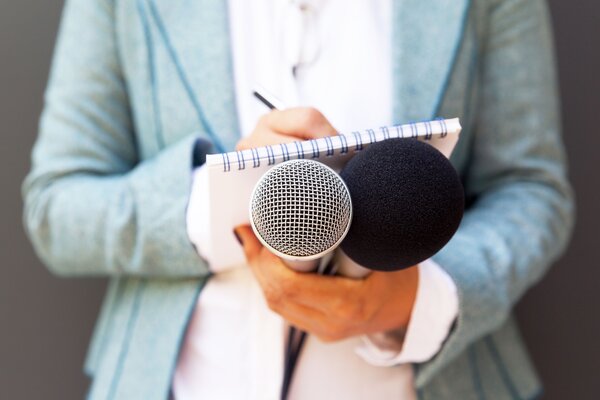 Bild vergr&ouml;&szlig;ern: Pressesprecher:in mit Notizblock, Stift und Mikrofon